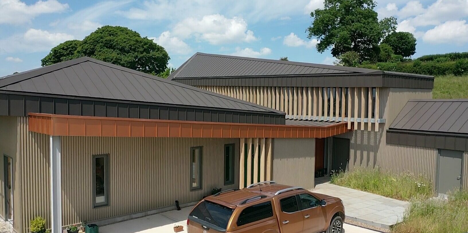 Entrance area of a longhouse in Derbyshire with parking space and a car