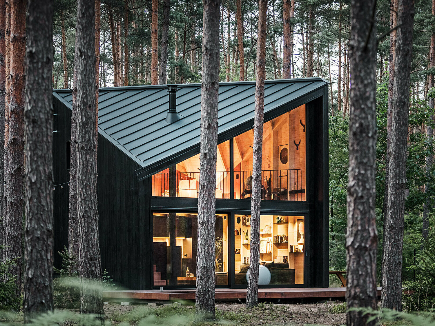 Side view of the glazed building front and into its lighted, Scandinavian-inspired interior.