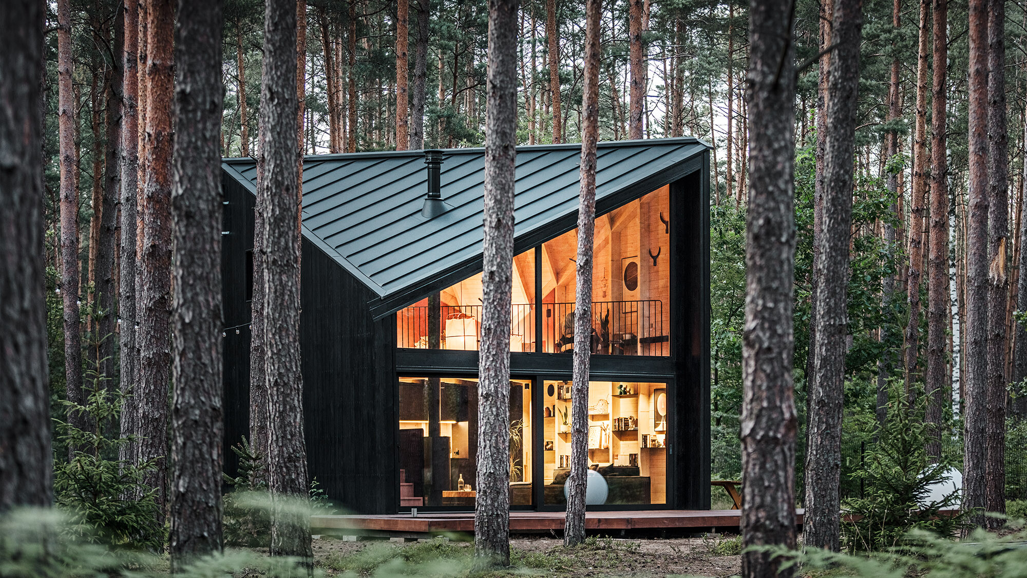 Side view of the glazed building front and into its lighted, Scandinavian-inspired interior.