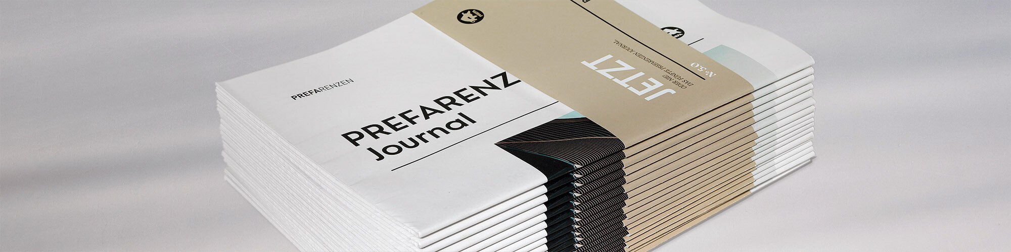 Side view of a stack of PREFARENZEN journals with the light ochre banderole that reads: "Now or never!"
