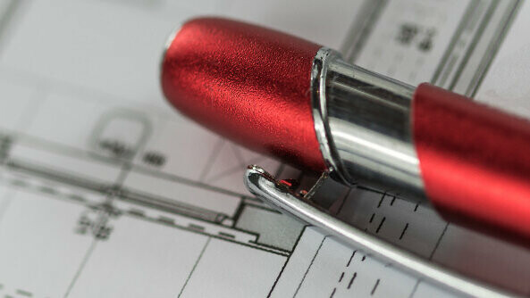 Red PREFA ballpoint pen on a plan