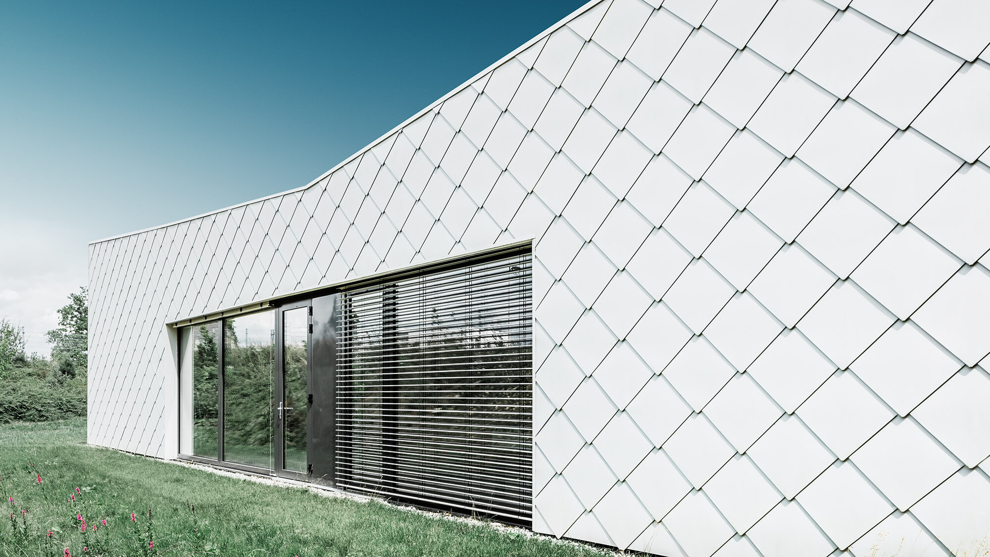 The rhomboid façade tile from the side, with the evenly laid rhomboid façade tiles in view.