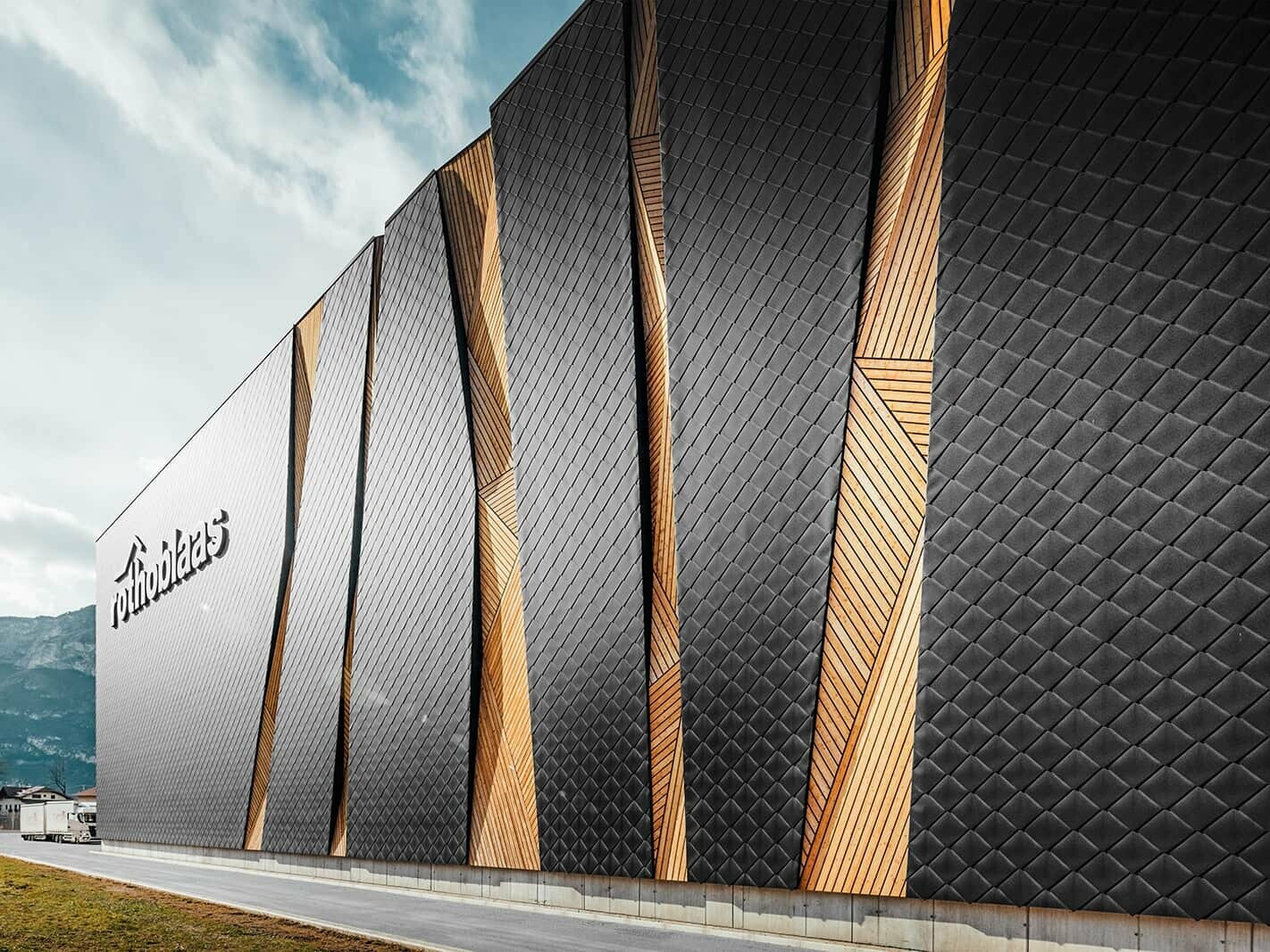 Side elevation of the Rothoblaas industrial building with PREFA Rhomboid façade tile 44 × 44 in P.10 black.
