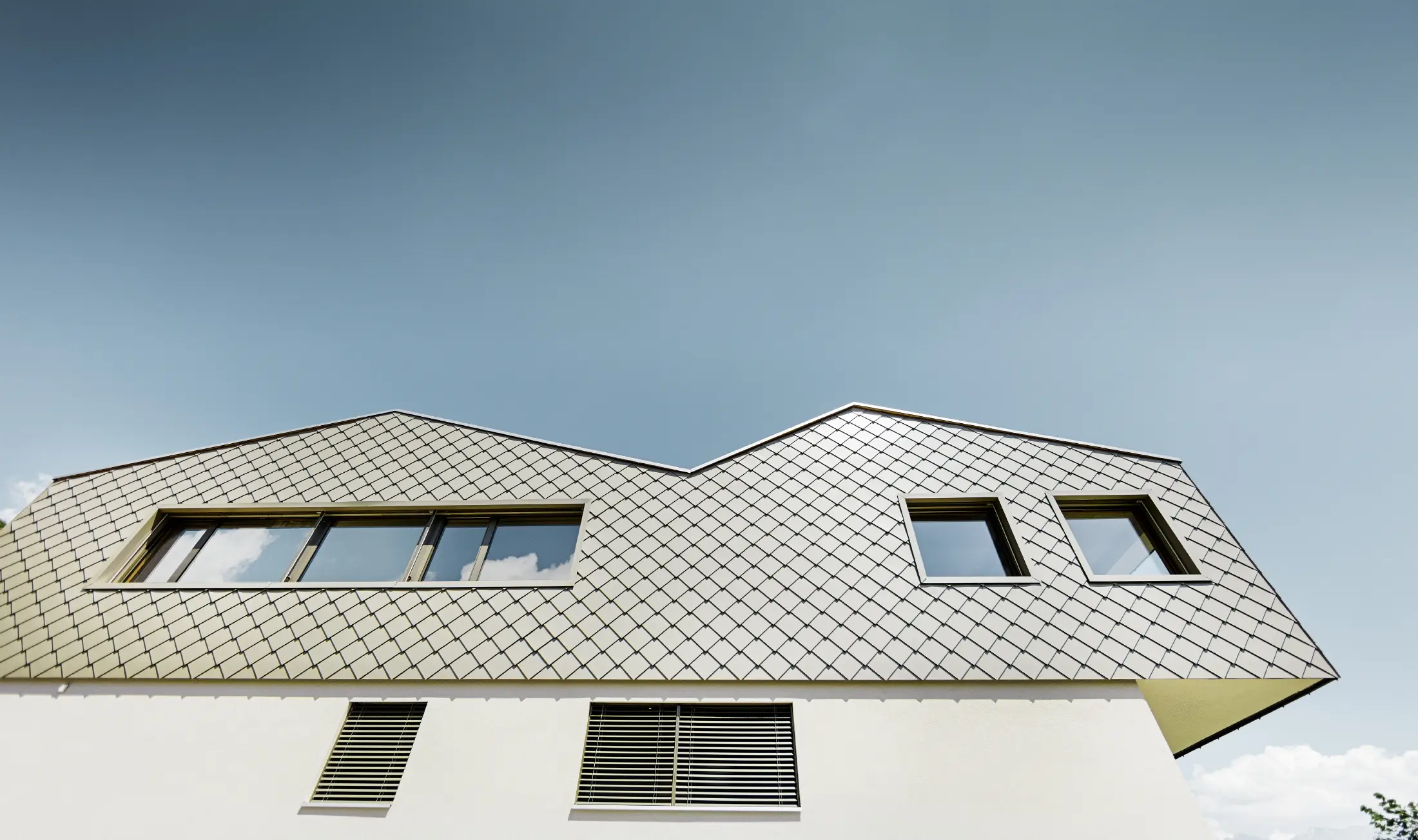 Modern detached house in the middle of the vineyards of the Rhône Valley with 4 different roof surfaces and an open gallery with a rhomboid tile façade in bronze