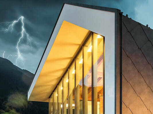 Photo of a modern house without eaves with thunderstorm in the background with lightning