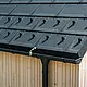 Close-up of PREFA roof tile R.16 with snow guards, gutter and downpipe in black P.10 incl. lightning protection and a vertical wooden façade