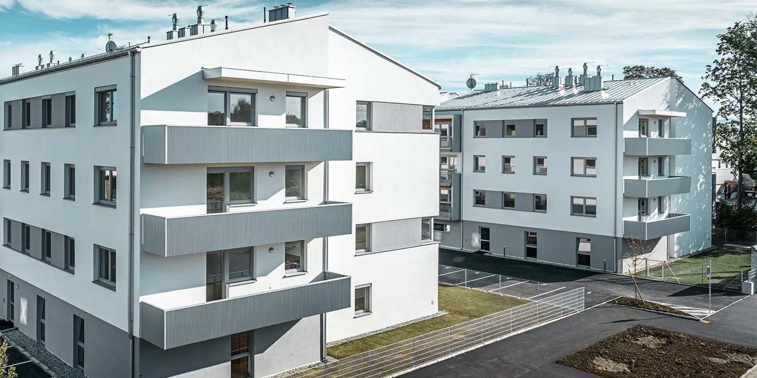 Modern apartment complex with a white façade and balconies with a PREFA serrated profile in metallic silver