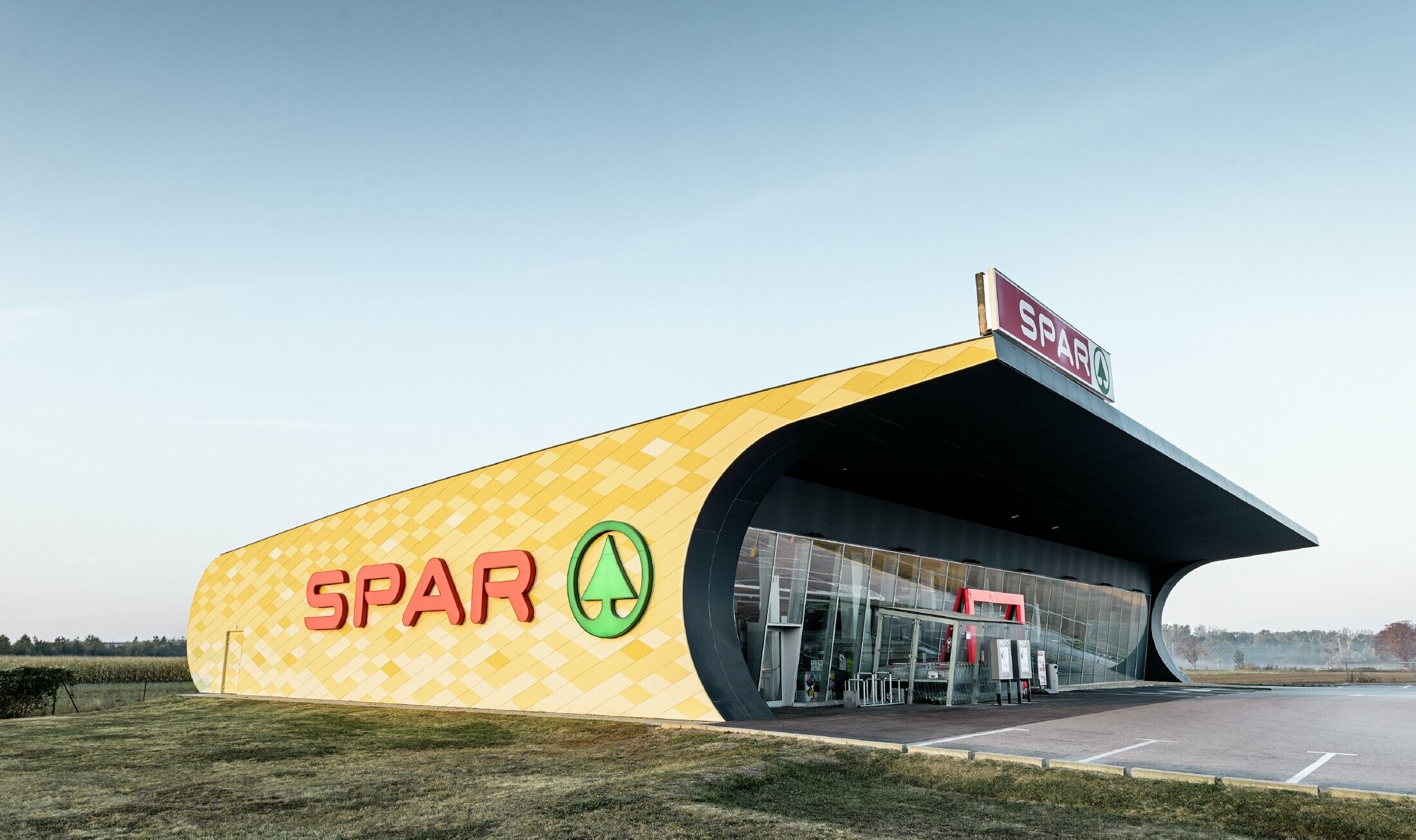 Spar branch with an aluminium façade in yellow and orange check and the Spar logo