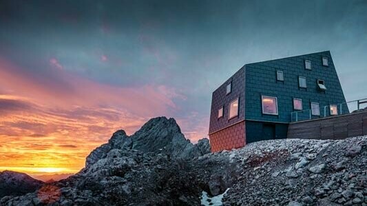 Exceptional architecture in the mountains: the Seethalerhütte on the Dachstein covered with PREFA FX.12 roof and façade panels in stone grey.