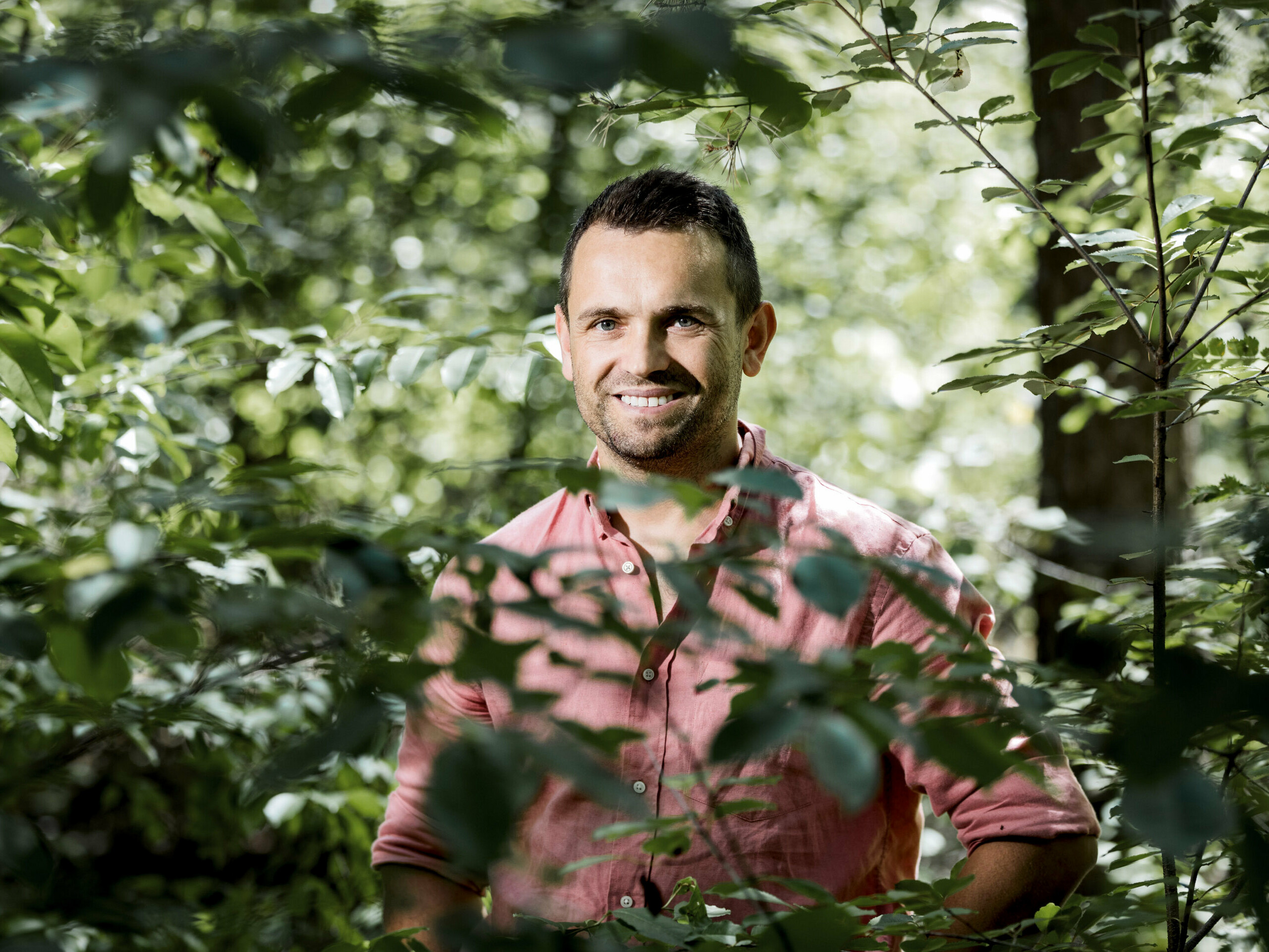 Portrait of the owner of the Rafał Stramski Boroteka, smiling in the forest.