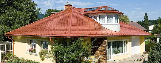 Detached house with hipped roof and dormers with PREFA brick red tile-effect aluminium shingles.