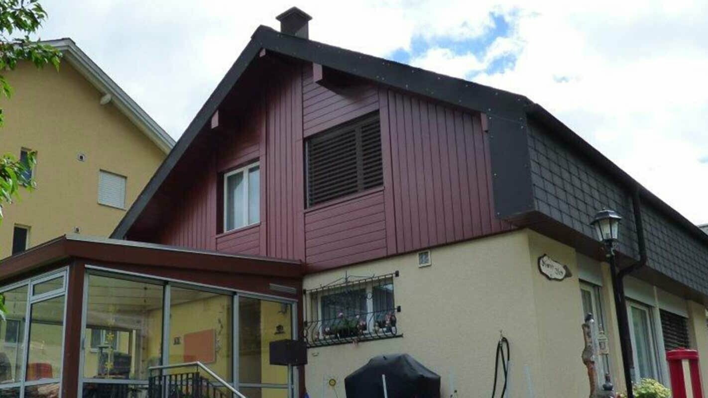 Renovation of gable façade with wood-effect PREFA sidings, installed vertically with conservatory and yellow façade