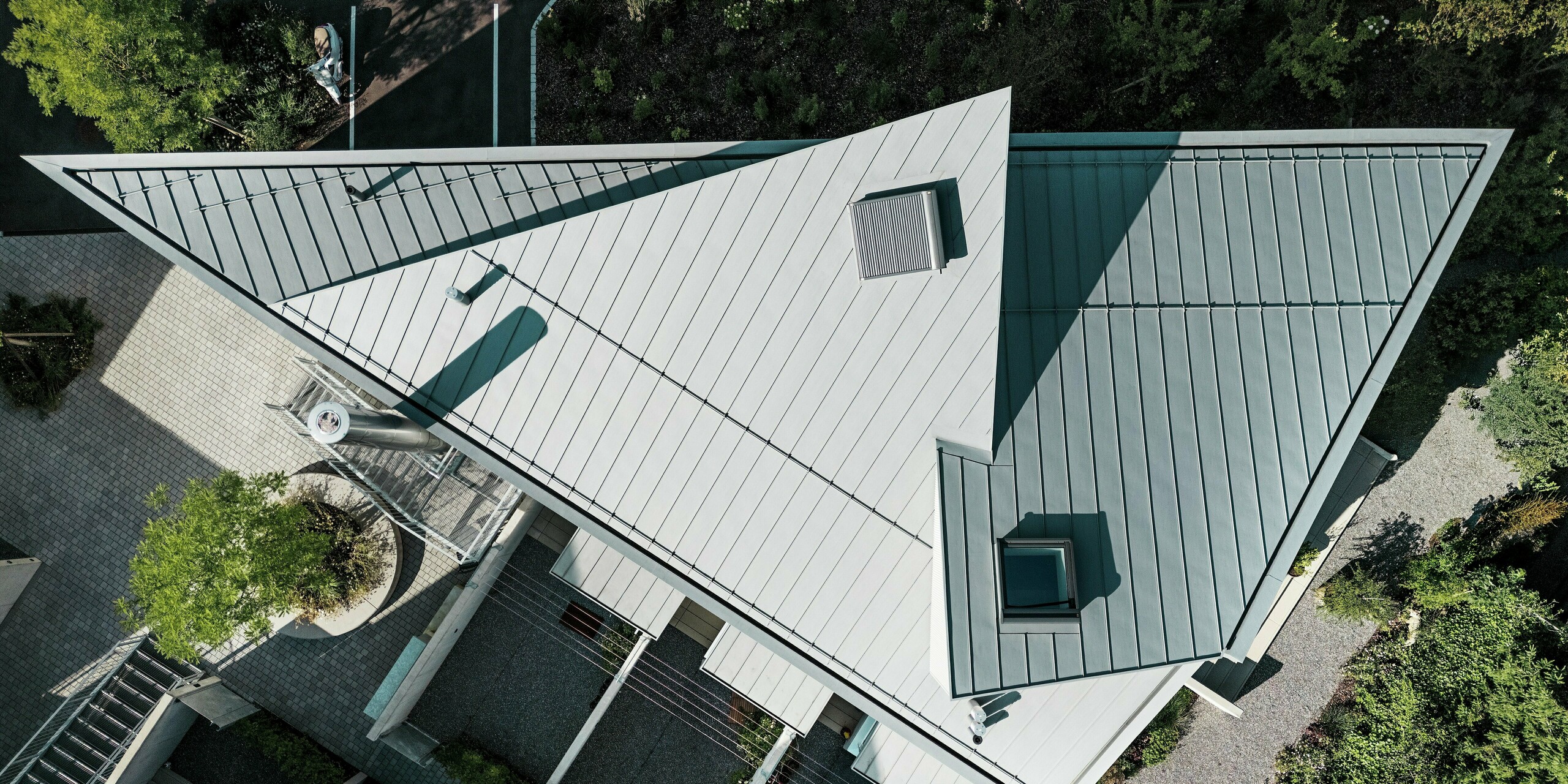 Draufsicht auf das markant gefaltete PREFALZ Dach in Patinagrau eines Tiny Homes in der Schweiz. Die präzise Ausführung in Stehfalztechnik unterstreicht die außergewöhnliche Geometrie des Baukörpers. PREFALZ überzeugt durch Flexibilität in der Gestaltung, extreme Wetterbeständigkeit und eine hochwertige Aluminium-Oberfläche für langlebige Dachlösungen.