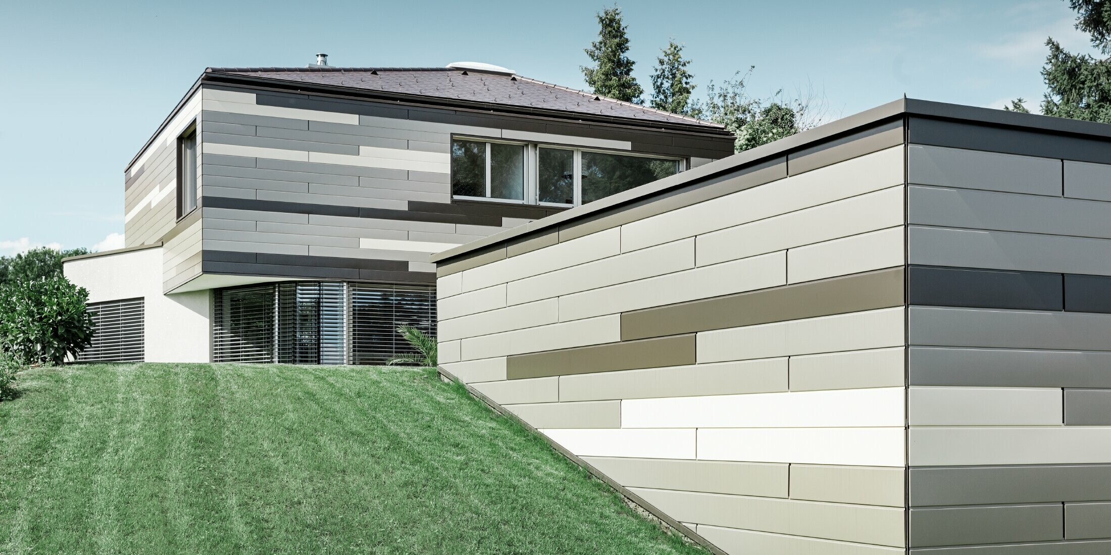 Modern detached house with a flat roof and covered terrace with an individually designed PREFA aluminium façade made of sidings in brown, bronze and ivory