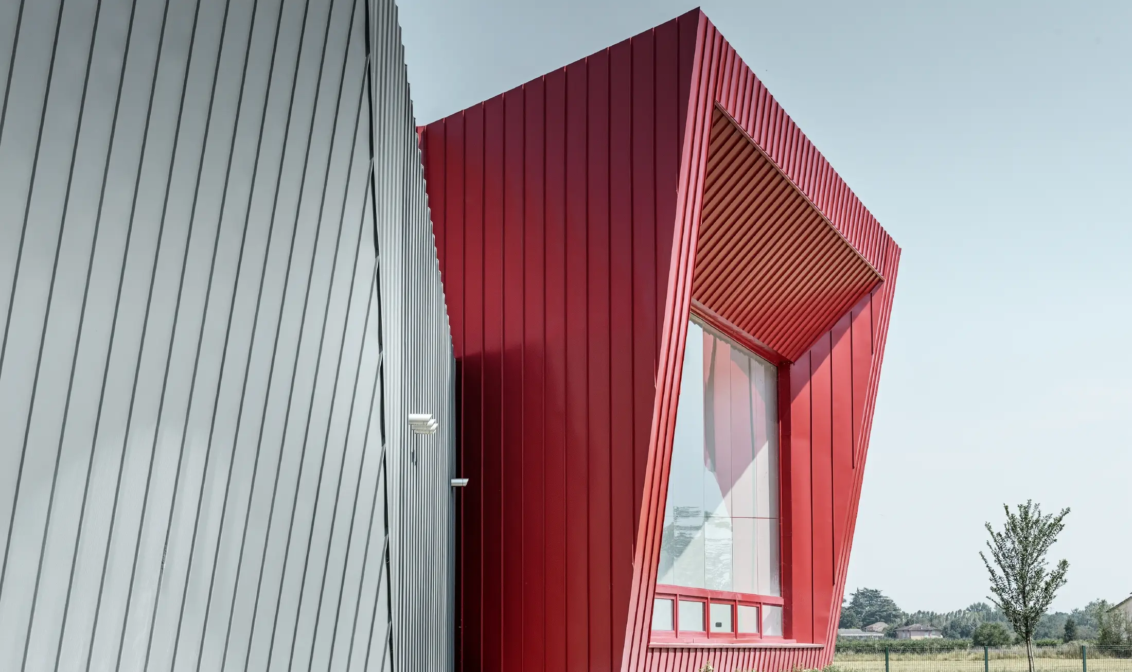 modern training centre by Dieci in Montecchio Emilia, Italy, with grandstand with aluminium façade with Prefalz standing seam in light grey and Falzonal in carmine red 