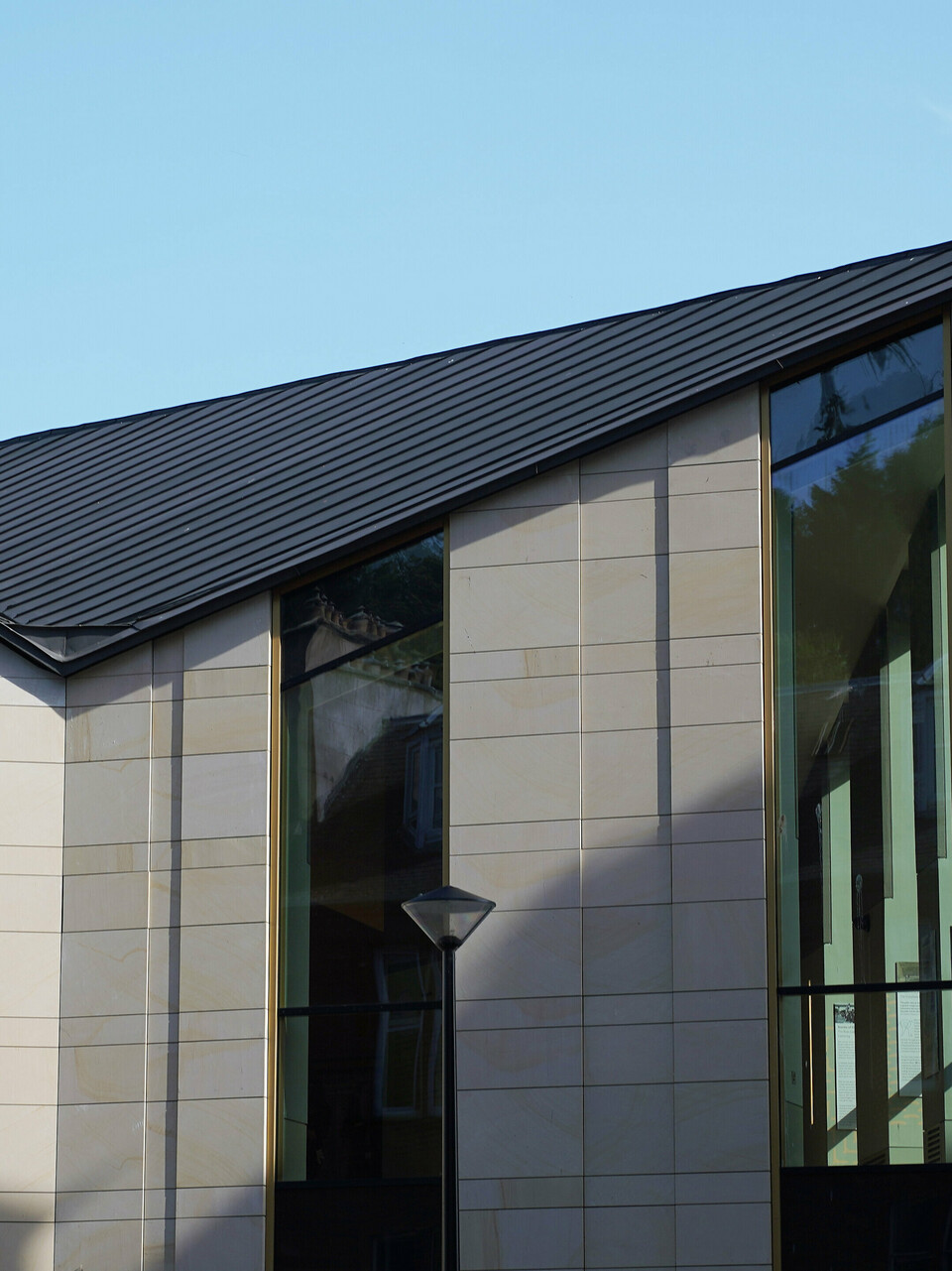 Side view of 'The Great Tapestry of Scotland' museum in Galashiels, which is characterised by a modern PREFALZ roof in P.10 zinc grey. The roof with its clear, geometric lines forms an attractive contrast to the traditional sandstone façades of the neighbouring buildings. The unique roof construction with its striking edges gives the building a contemporary flair and emphasises the combination of historical architecture and modern design.