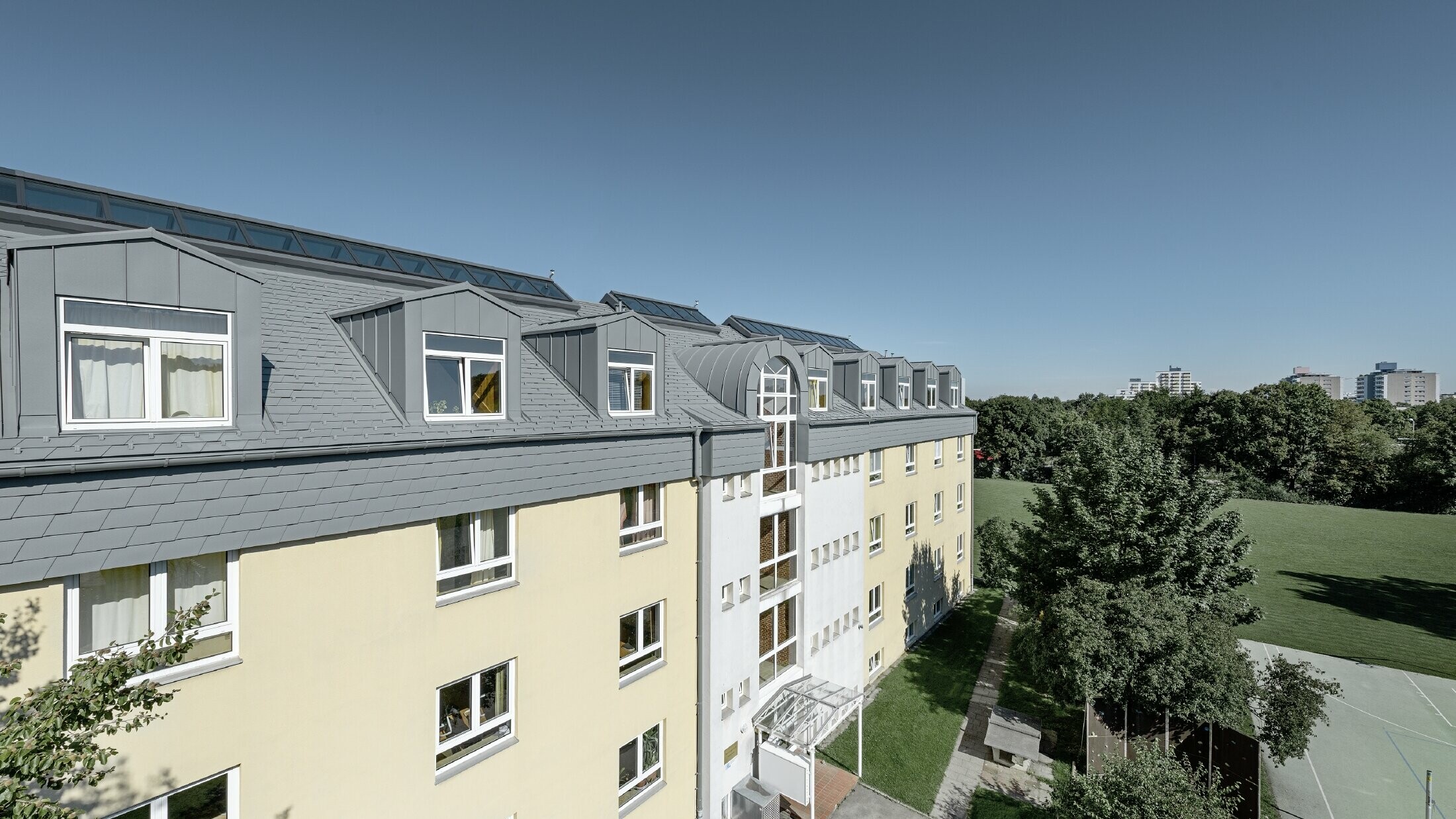 Top floor of the Albertinum building in Munich (Germany) with PREFA shingle and standing seam in light grey