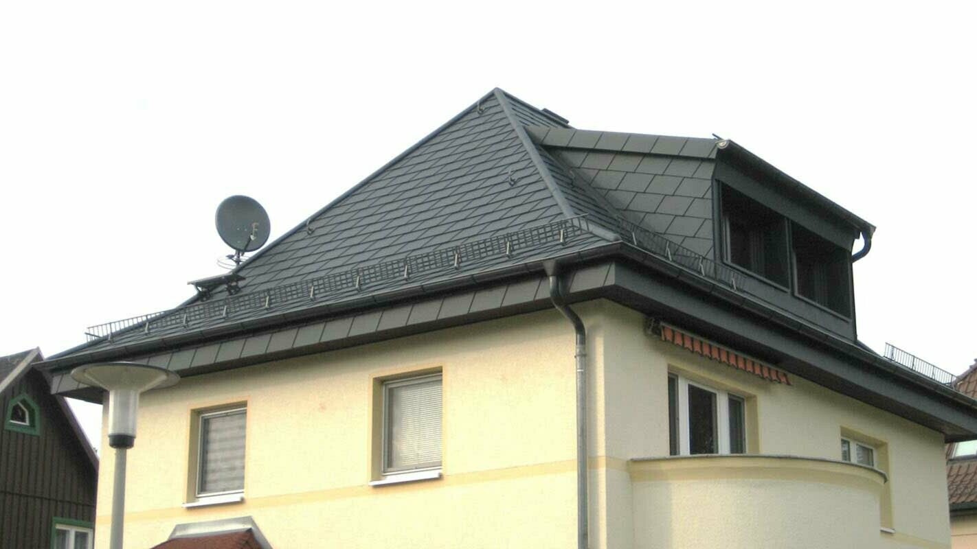Hipped roof renovation with PREFA shingles and dormer, yellow façade