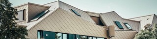 The rhomboid-shaped 44 × 44 façade tile in the special P.10 Bronze coating stretches over the entire structure like a uniform skin and gives the surface a pearly quality.