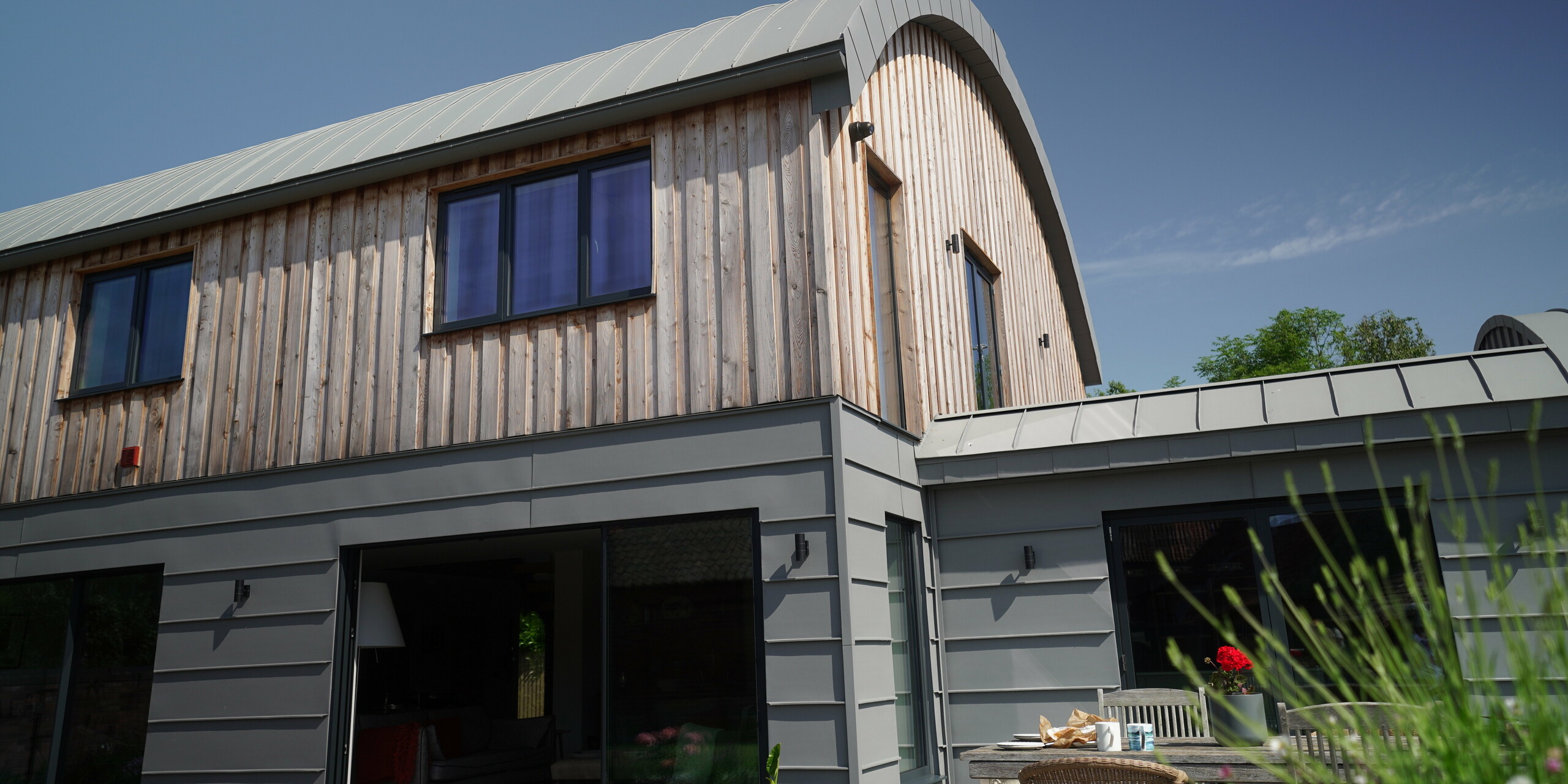 Close-up of a Dutch barn in Syerston with building envelope made of PREFALZ in patina grey and wood