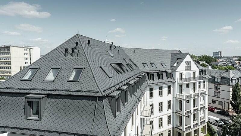 In this picture you can see the "Marie" building, which is roofed in rhomboid roof tiles 29x 29 and Prefalz in dark grey