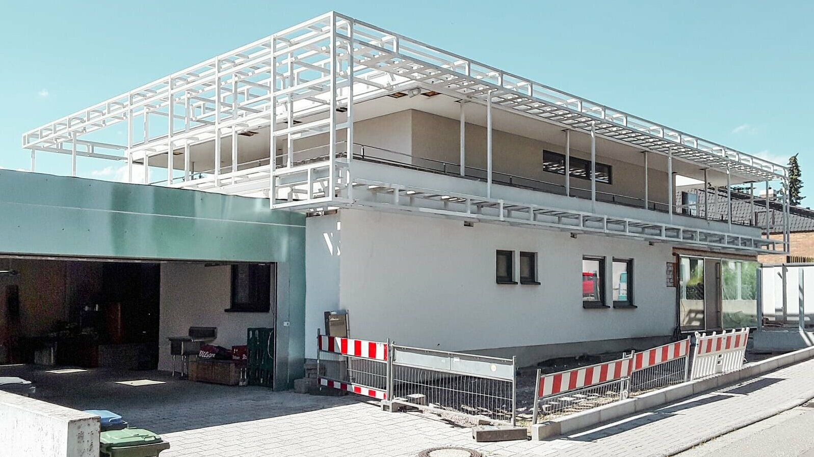 construction site view, street side, garage, scaffolding on building, white plaster below, barrier in the front