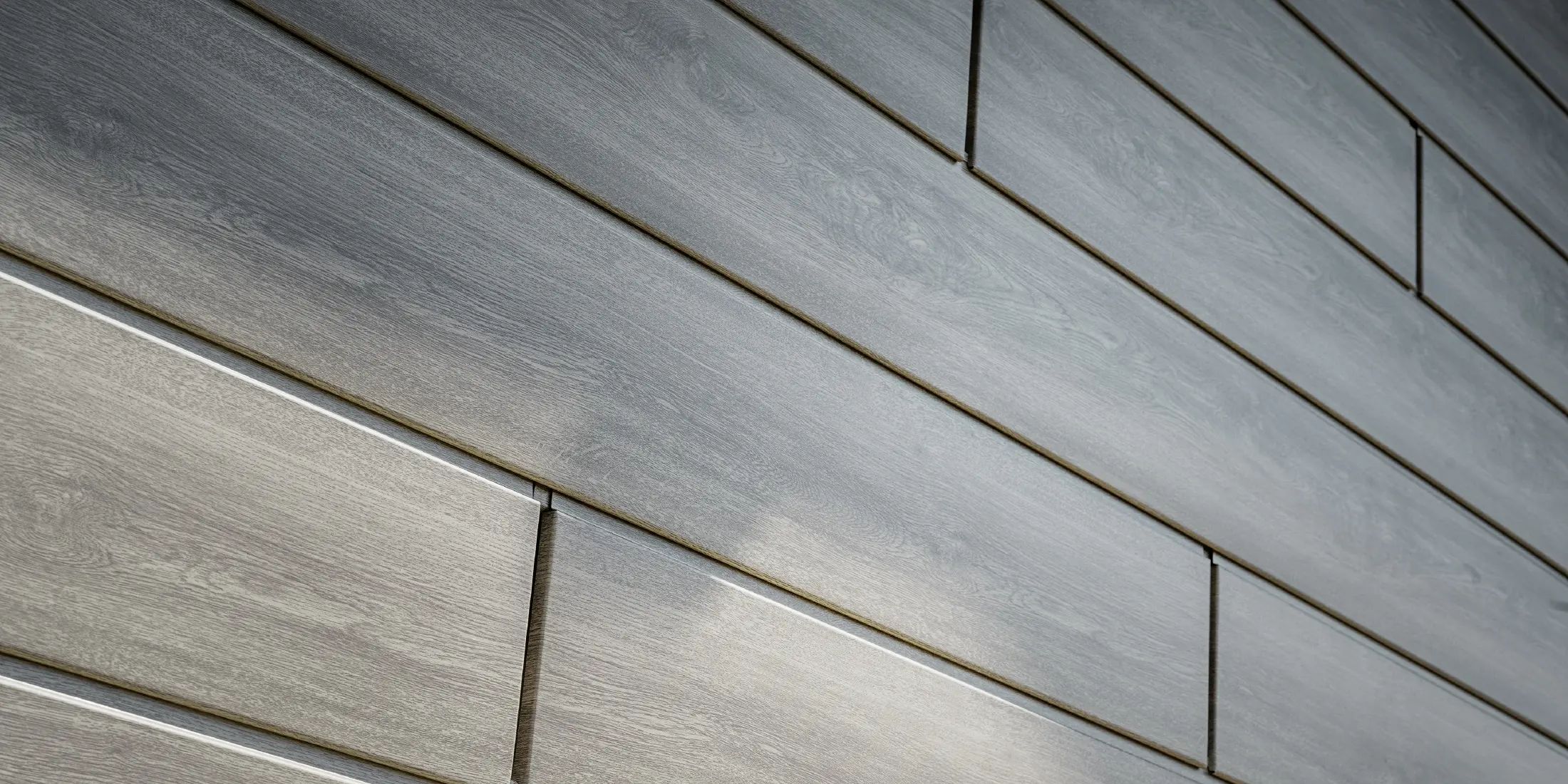 Close-up of the PREFA aluminium façade siding; the aluminium panels were installed horizontally and have a wood-effect finish in grey oak.