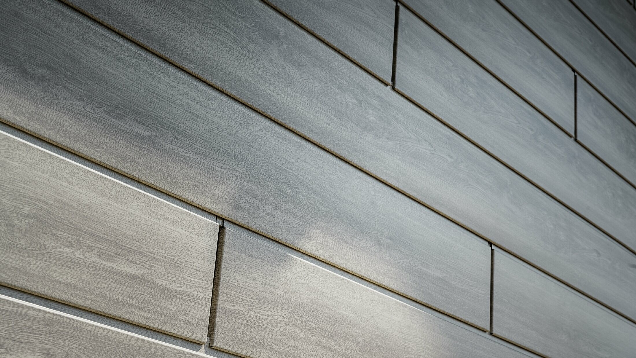 Close-up of the PREFA aluminium façade siding; the aluminium panels were installed horizontally and have a wood-effect finish in grey oak.