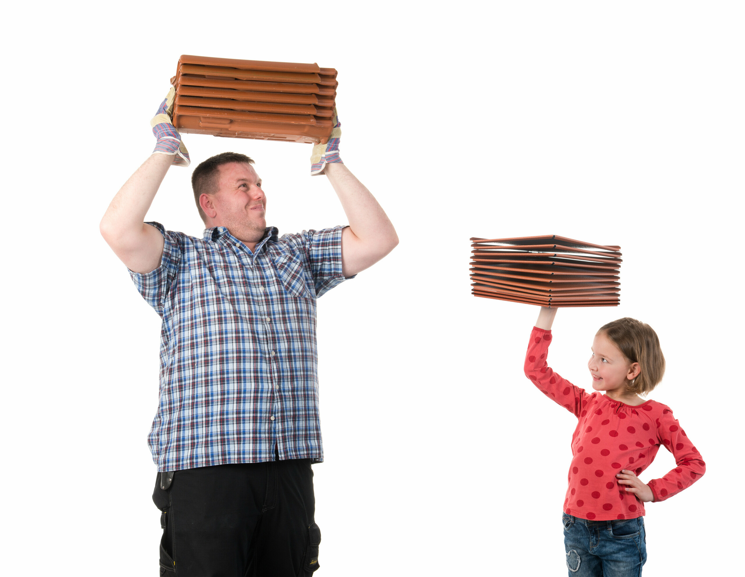 The advantage of lightweight PREFA products in comparison to conventional tiles — illustrated by a little girl, effortlessly holding up PREFA products with one hand, while a man struggles under the weight of heavy traditional tiles.