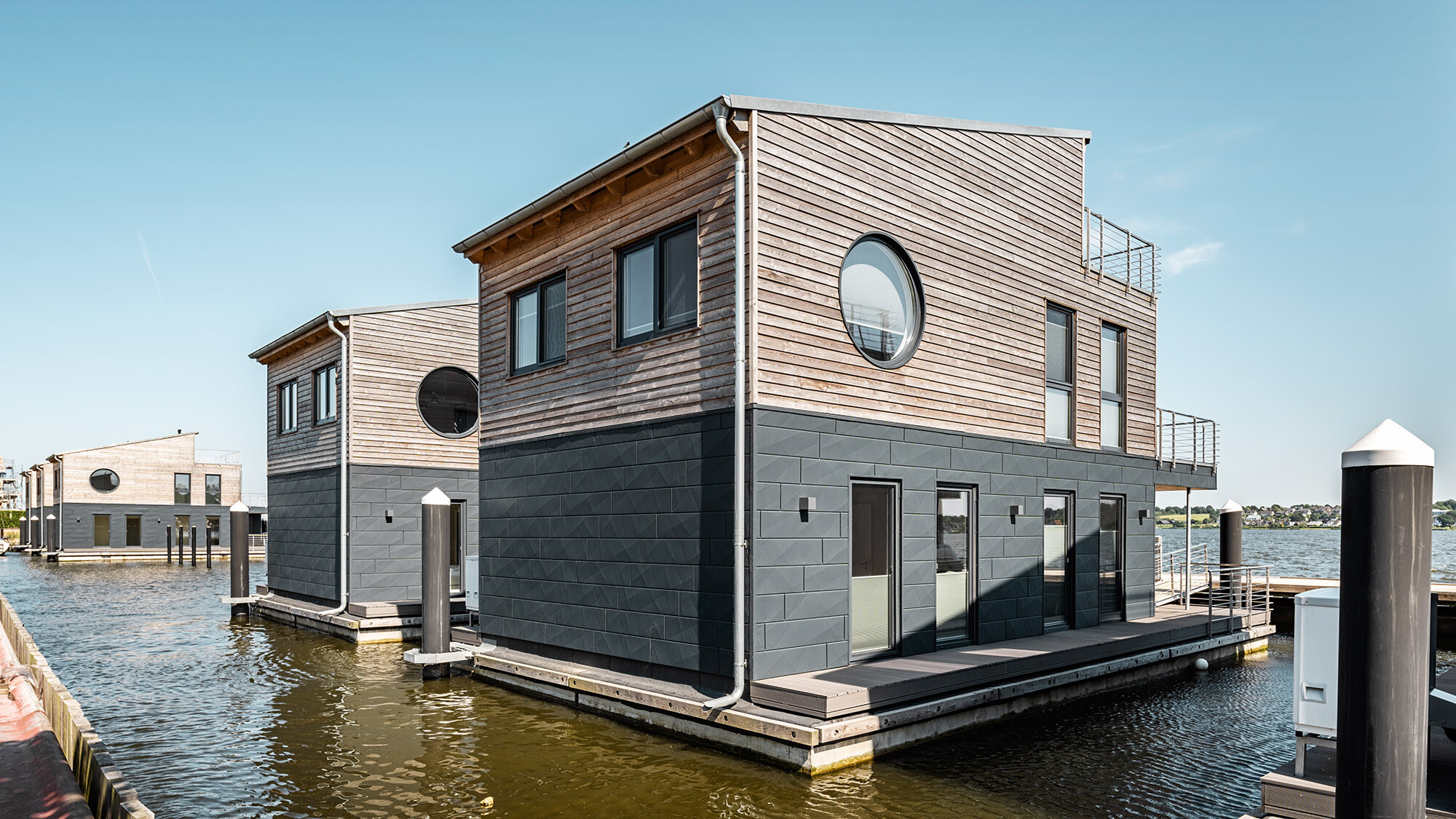 Two of the buildings from the back, the Schlei extending in front of the jetty before them.