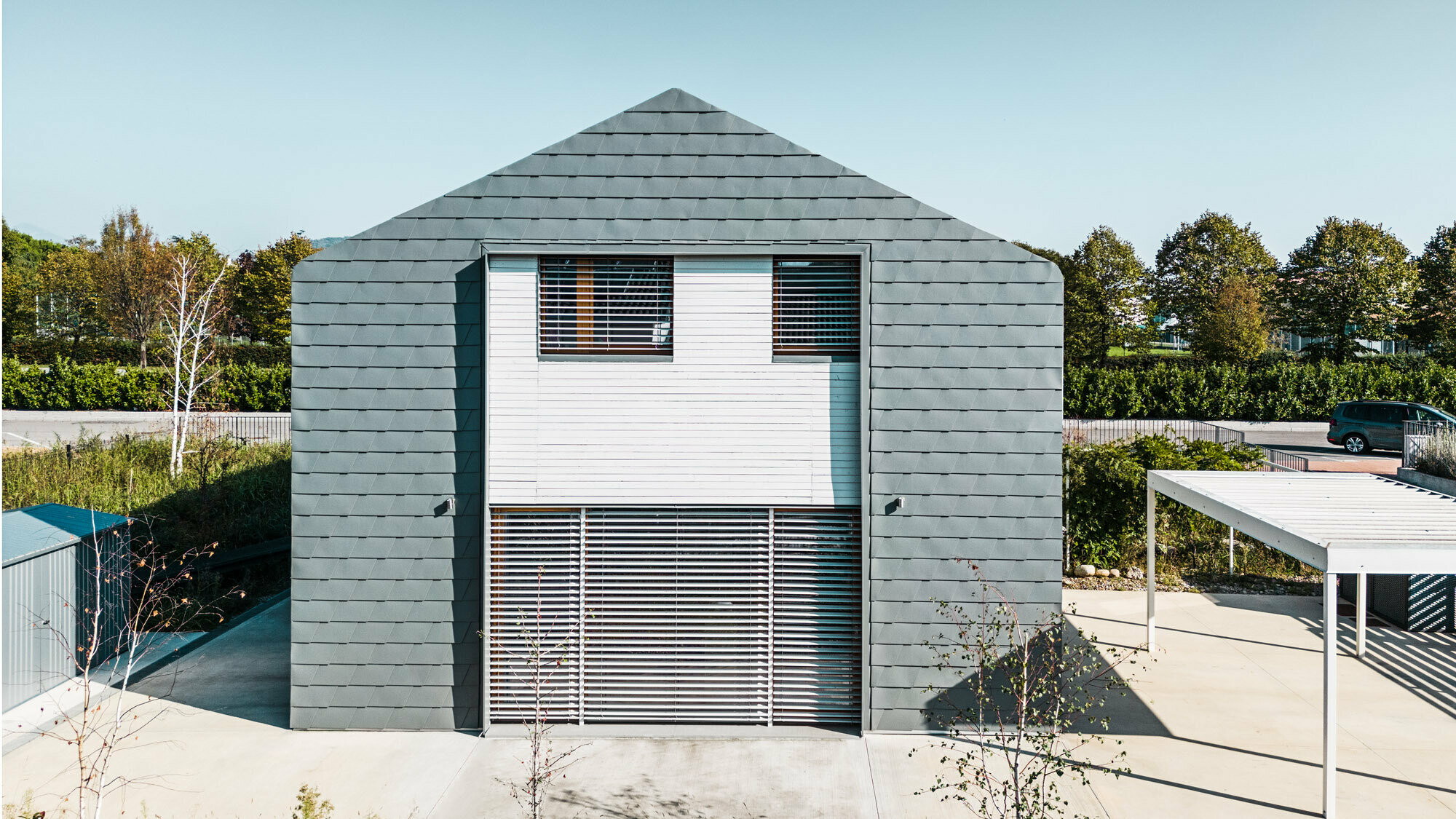 Front view of the house towards the property, another visual interruption of the façade through the white wooden slats.