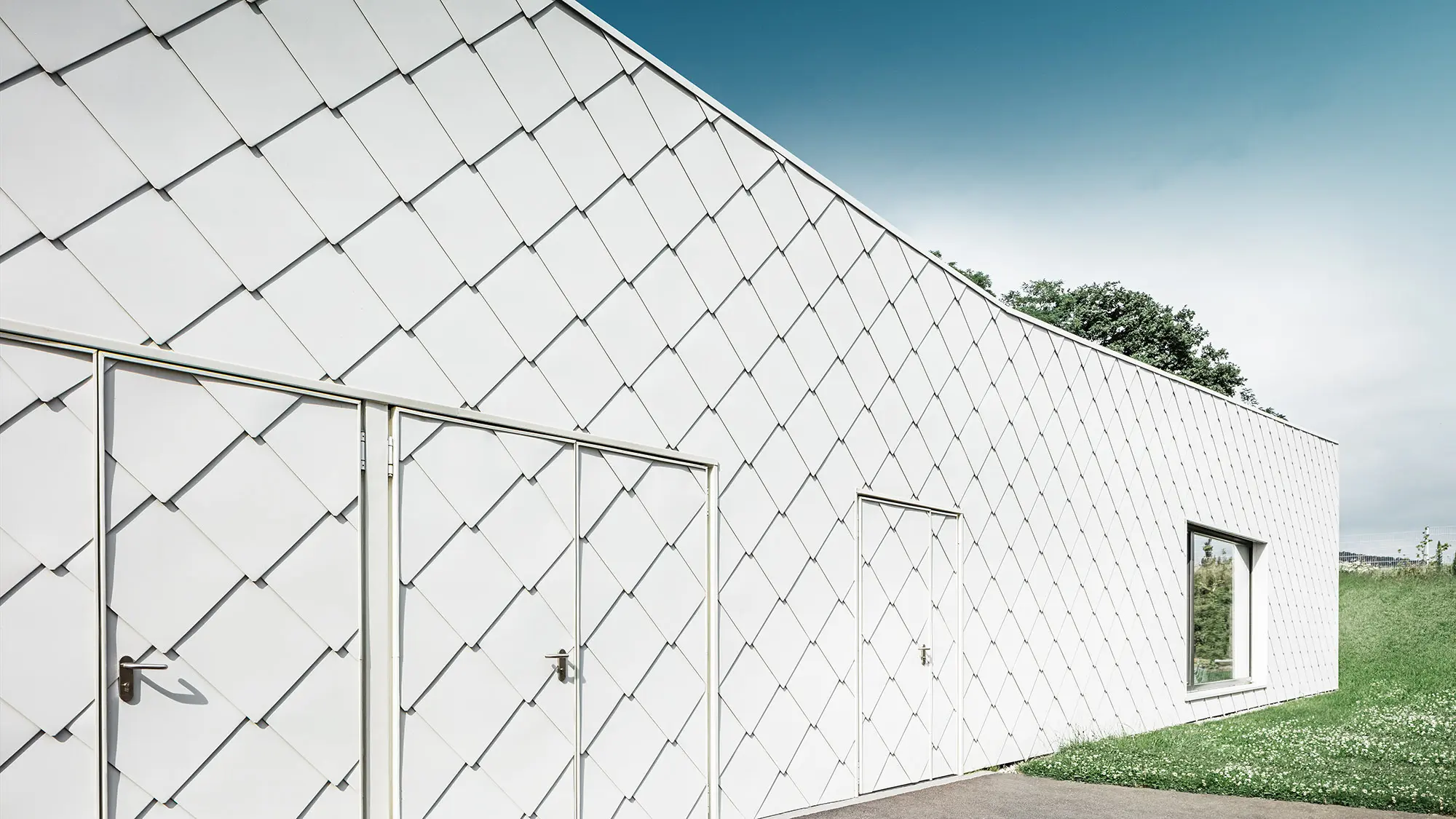 The rhomboid façade tile from the side, with the evenly laid rhomboid façade tiles in view.