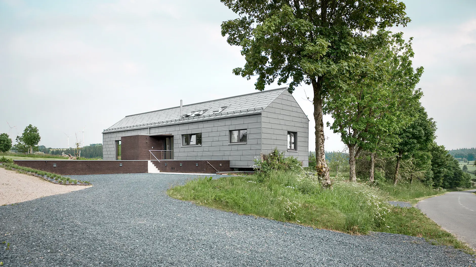 The bed and breakfast from a lateral street perspective including the driveway and trees on the side of the street, the structured aluminium can clearly be seen.