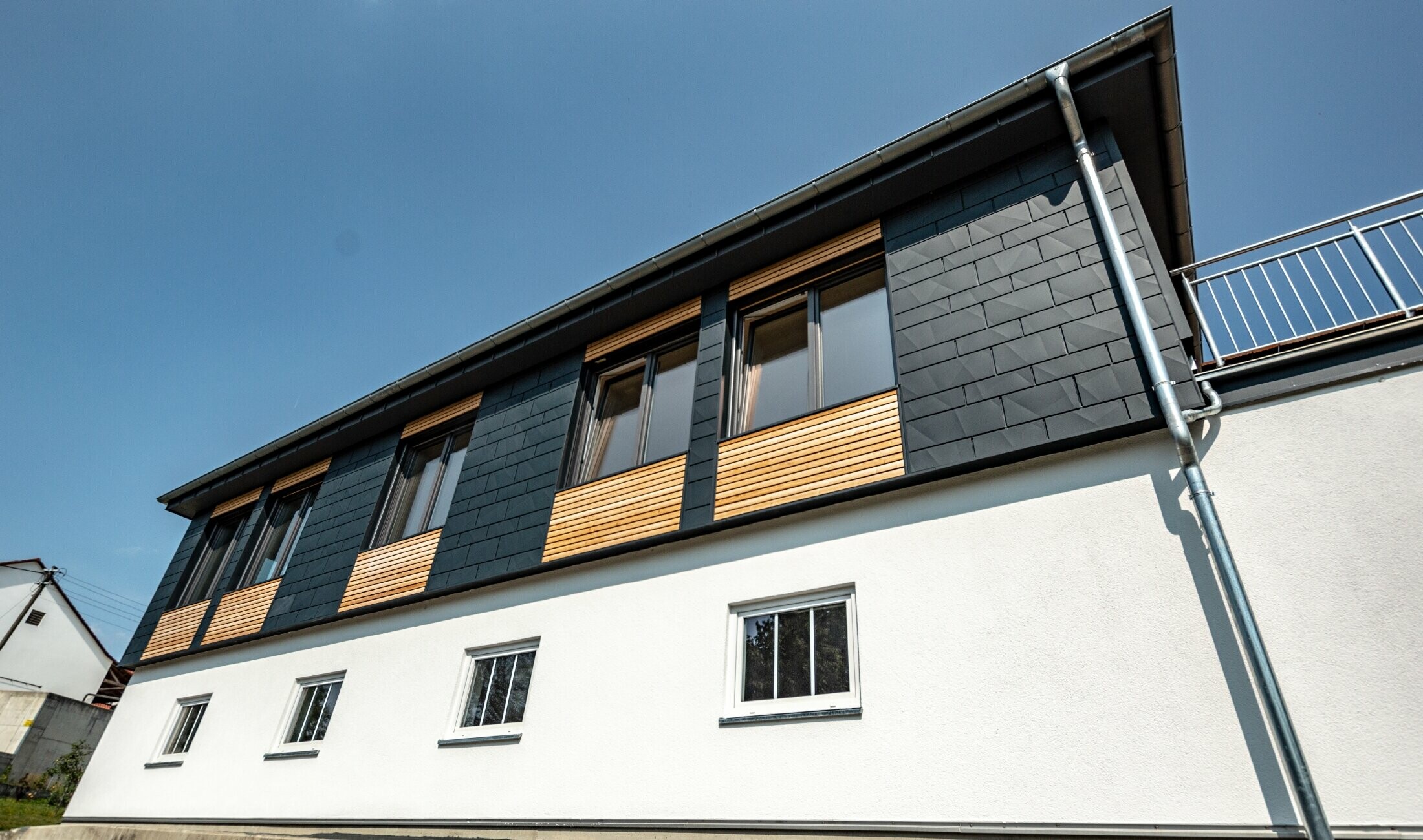 Façade design with various building materials: aluminium PREFA Siding.X in anthracite, a horizontal wooden façade and a white rendered façade were used.