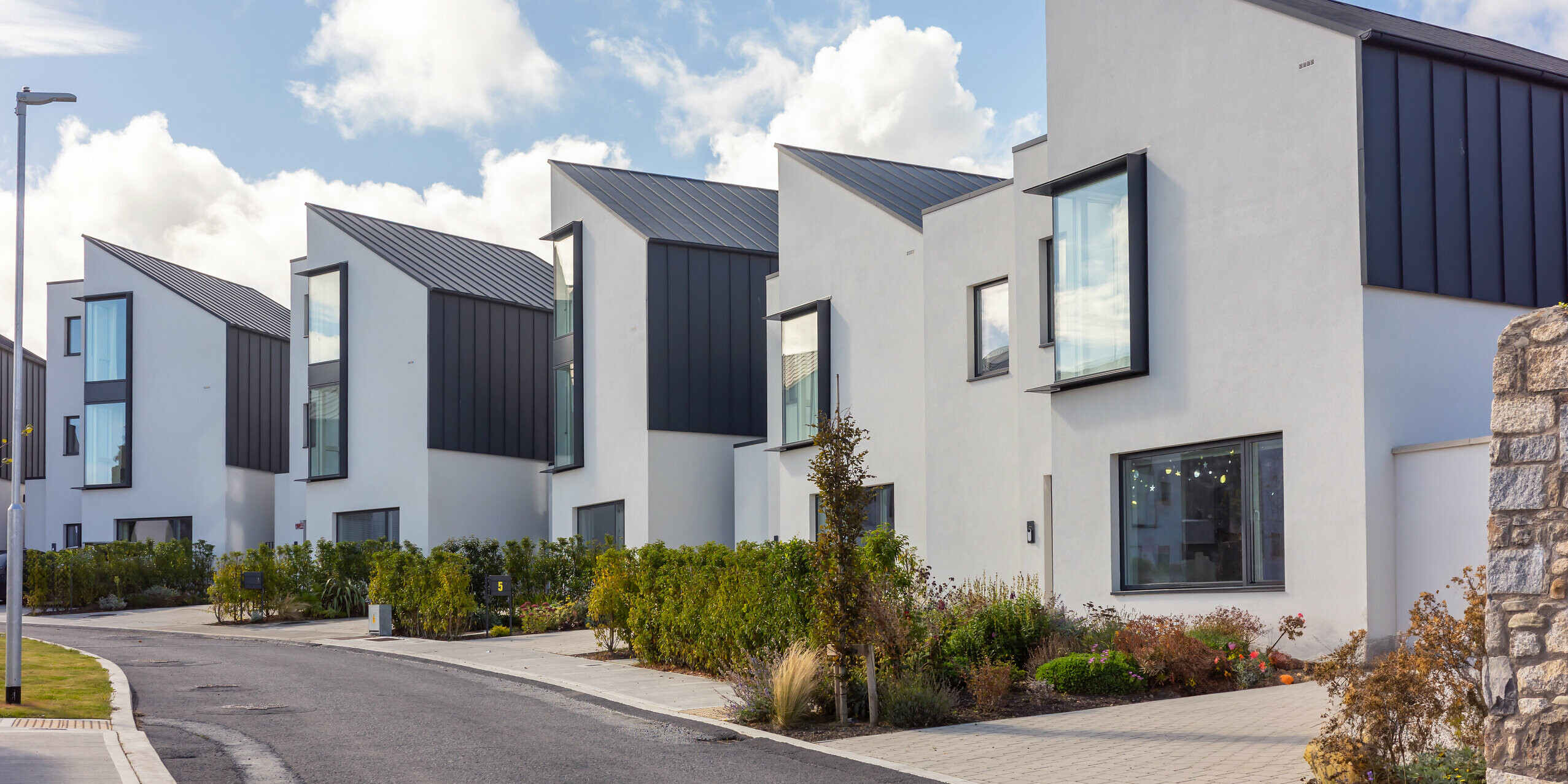 Terraced houses in Watson Place with clean, modern architecture and striking PREFALZ standing seam roofs and façades in P.10 anthracite. The sharply cut roof lines and large window elements add dynamic accents. The durable PREFA aluminium surfaces offer optimum weather protection and give the residential complex an elegant, timeless appearance.