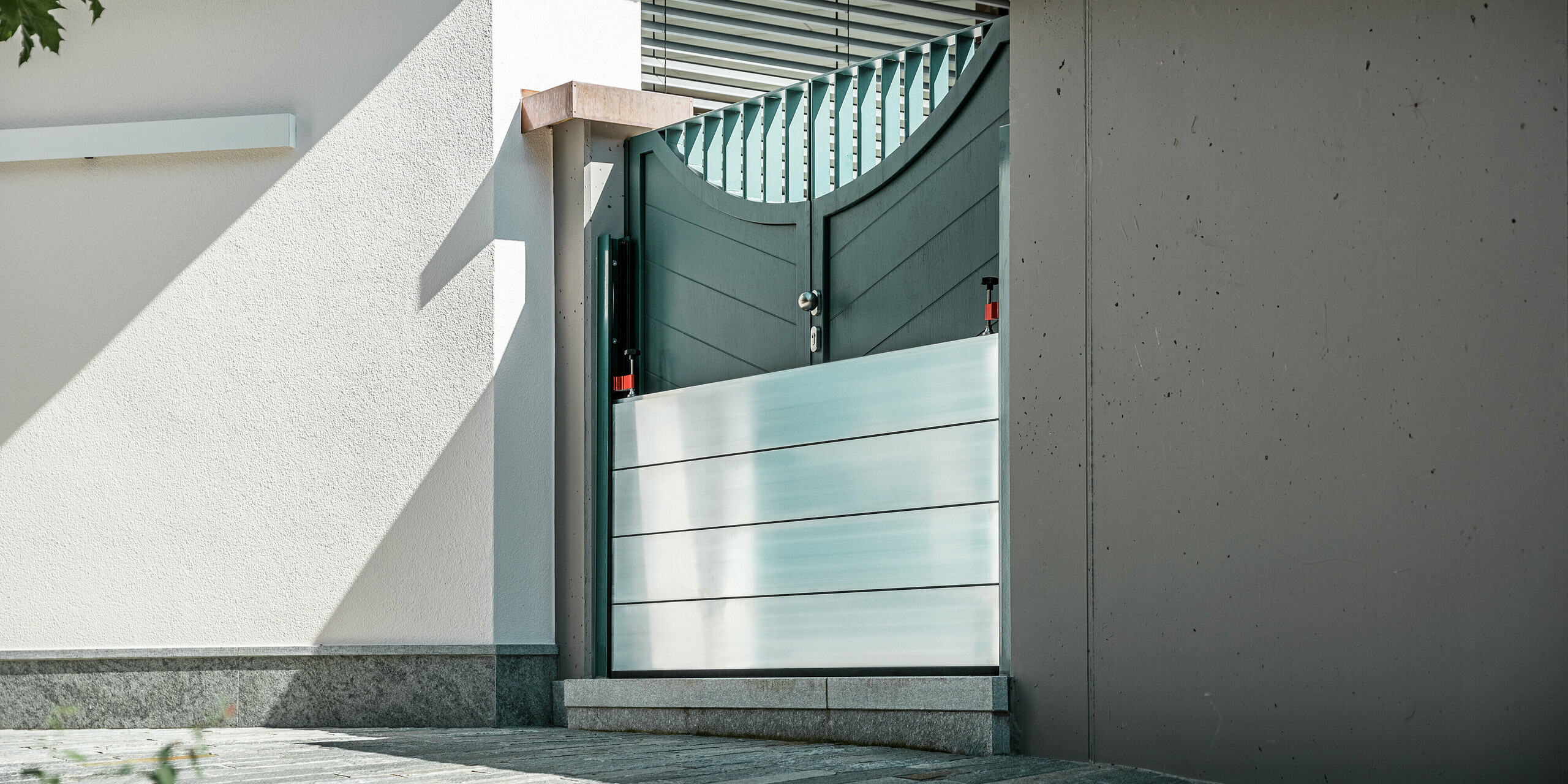 Nahaufnahme eines montierten PREFA Hochwasserschutzsystems am Gartentor eines Einfamilienhauses in Schwaz, Tirol. Die eingesetzten Dammbalken aus Aluminium sind in seitlich angebrachte Befestigungsprofile eingeschoben und schützen den Eingangsbereich zuverlässig vor eindringendem Wasser. Das System überzeugt durch seine schlichte Optik, die schnelle Einsatzbereitschaft und die korrosionsbeständigen Materialien - ideal für den privaten Objektschutz. Die Wandprofile sind in der gleichen Farbe wie die Tür gehalten, so dass ein harmonischer Gesamteindruck entsteht.