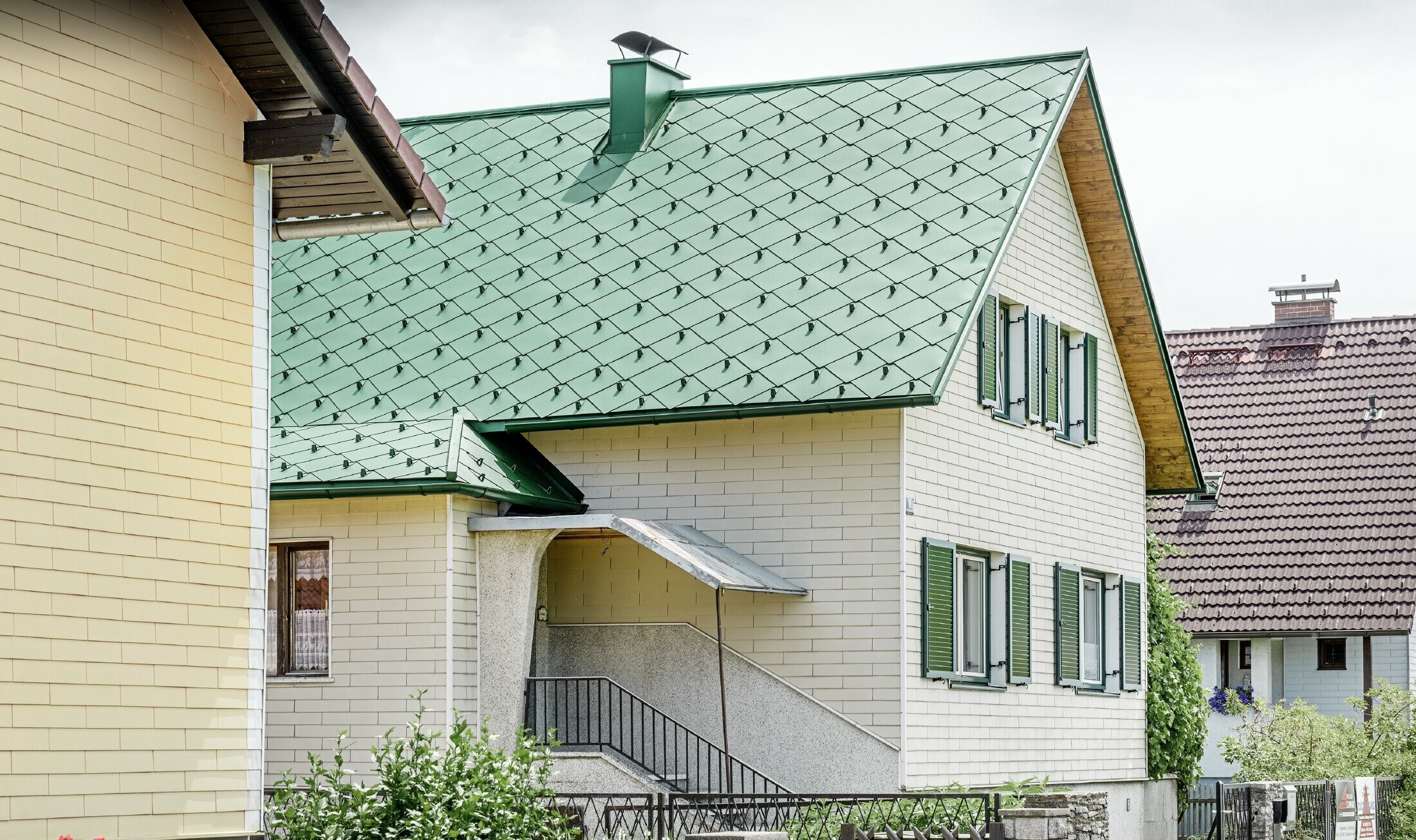 Classic detached house with a gable roof and a roof covering made of moss green aluminium with green shutters