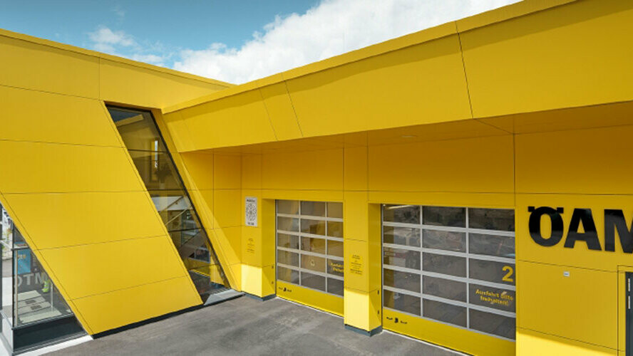 ÖAMTC support centre with rapeseed yellow PREFA composite panels installed as a non-bearing, rear-ventilated façade.