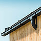House corner with PREFA box gutter in black, with gutter box, fastened with PREFA gutter brackets, façade clad with wood.