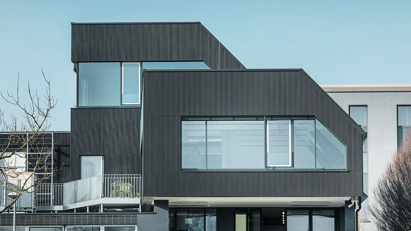 Side view of the Amann café on a sunny day. A corrugated profile in black was used to protect the building.