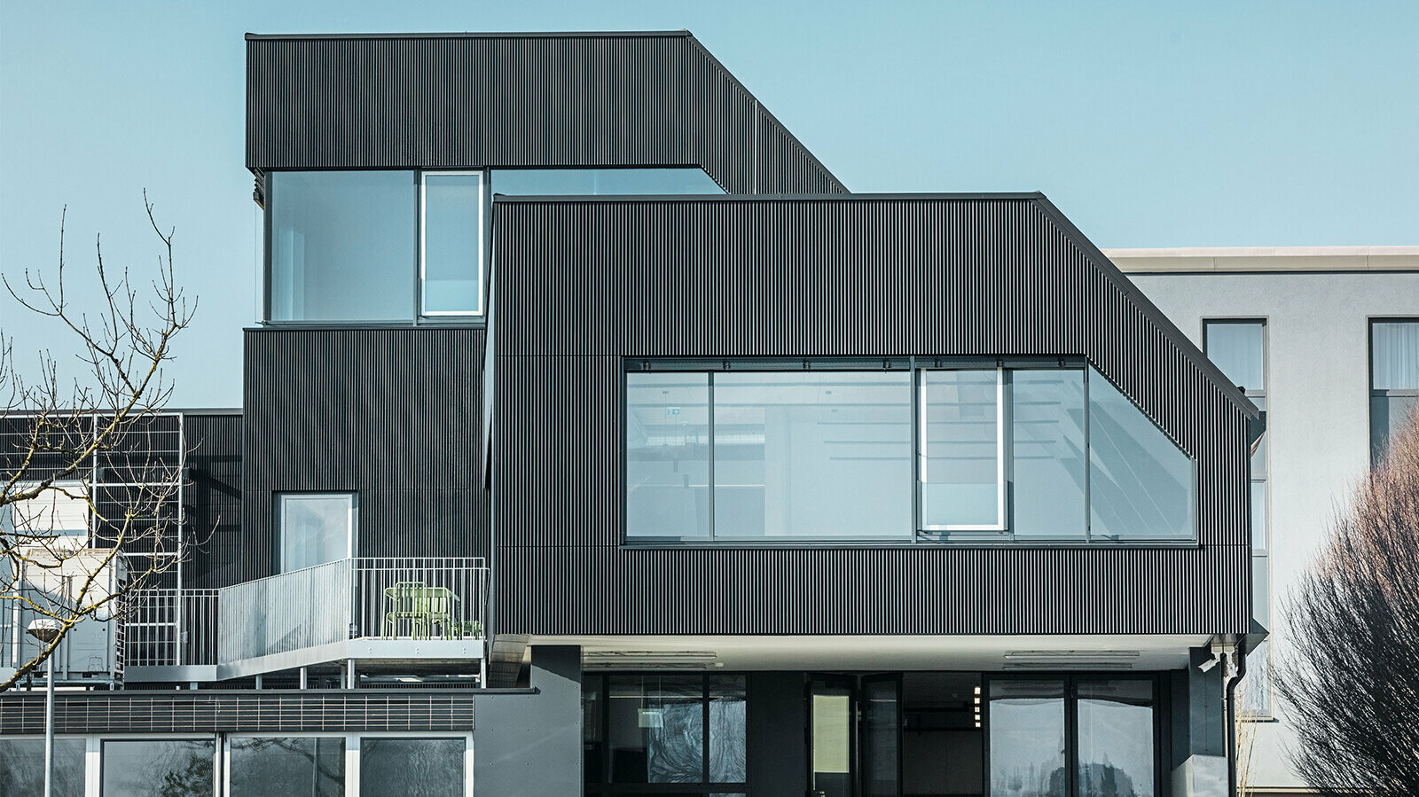 Side view of the Amann café on a sunny day. A corrugated profile in black was used to protect the building.