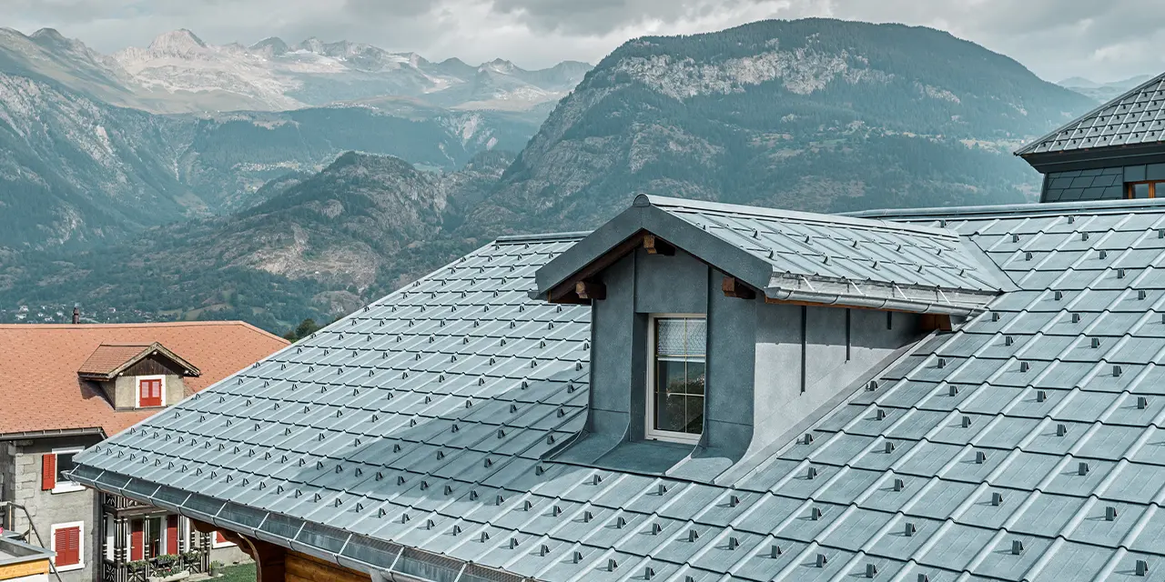 Gabled roof with dormers. A PREFA sheet metal roof is installed on the roof area with the roof tiles in stone grey. The dormer is clad in a PREFA angular standing seam in stone grey.