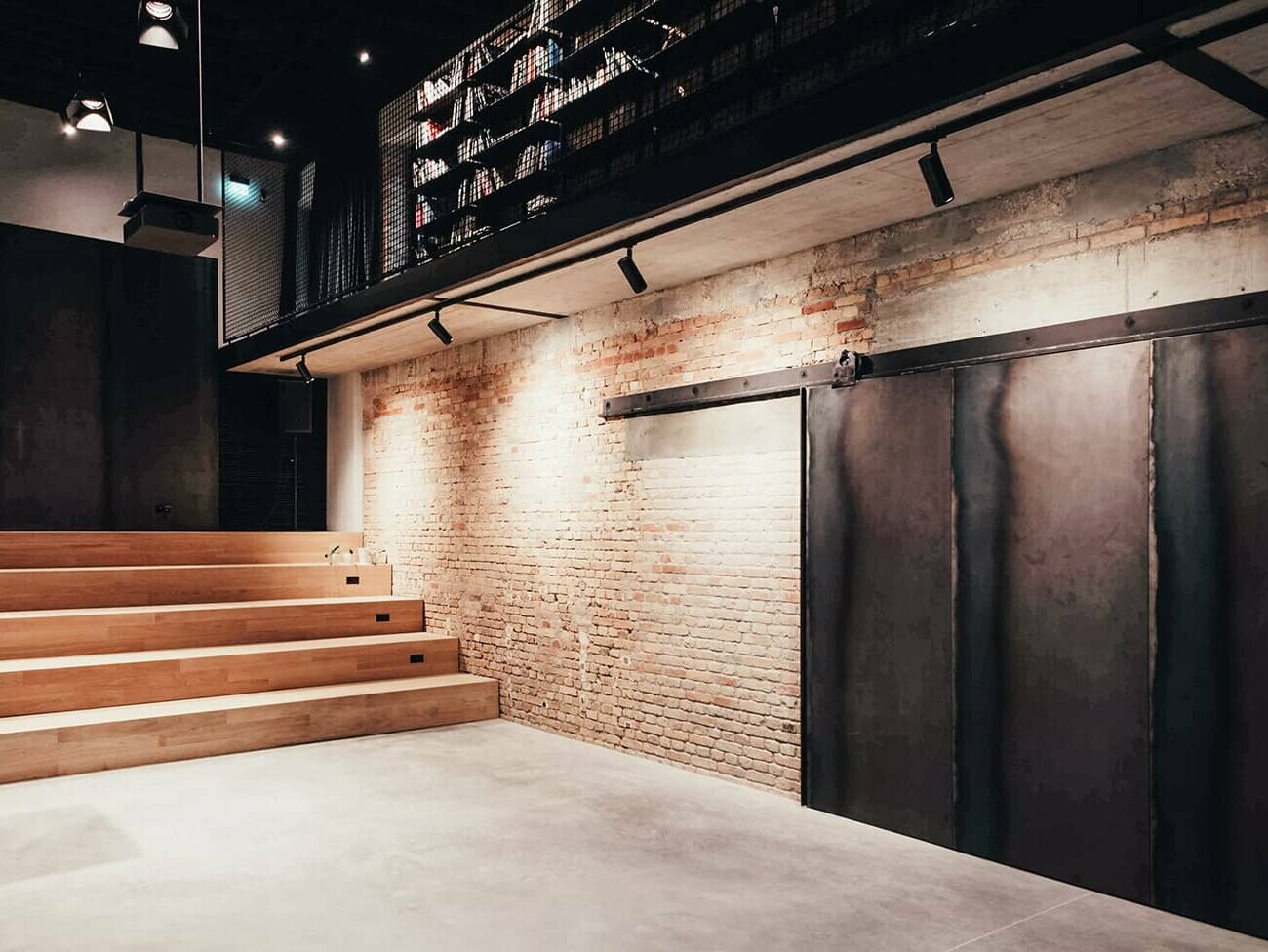 In this picture, a large black metal door can be seen, with stairs leading up on the left side. The whole room is pleasantly lit.