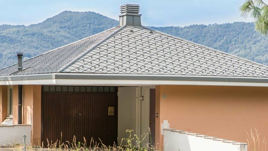 Orange-coloured detached home with a pavilion roof, which has been covered with PREFA 29 × 29 aluminium rhomboid roof tiles in the colour P.10 light grey.