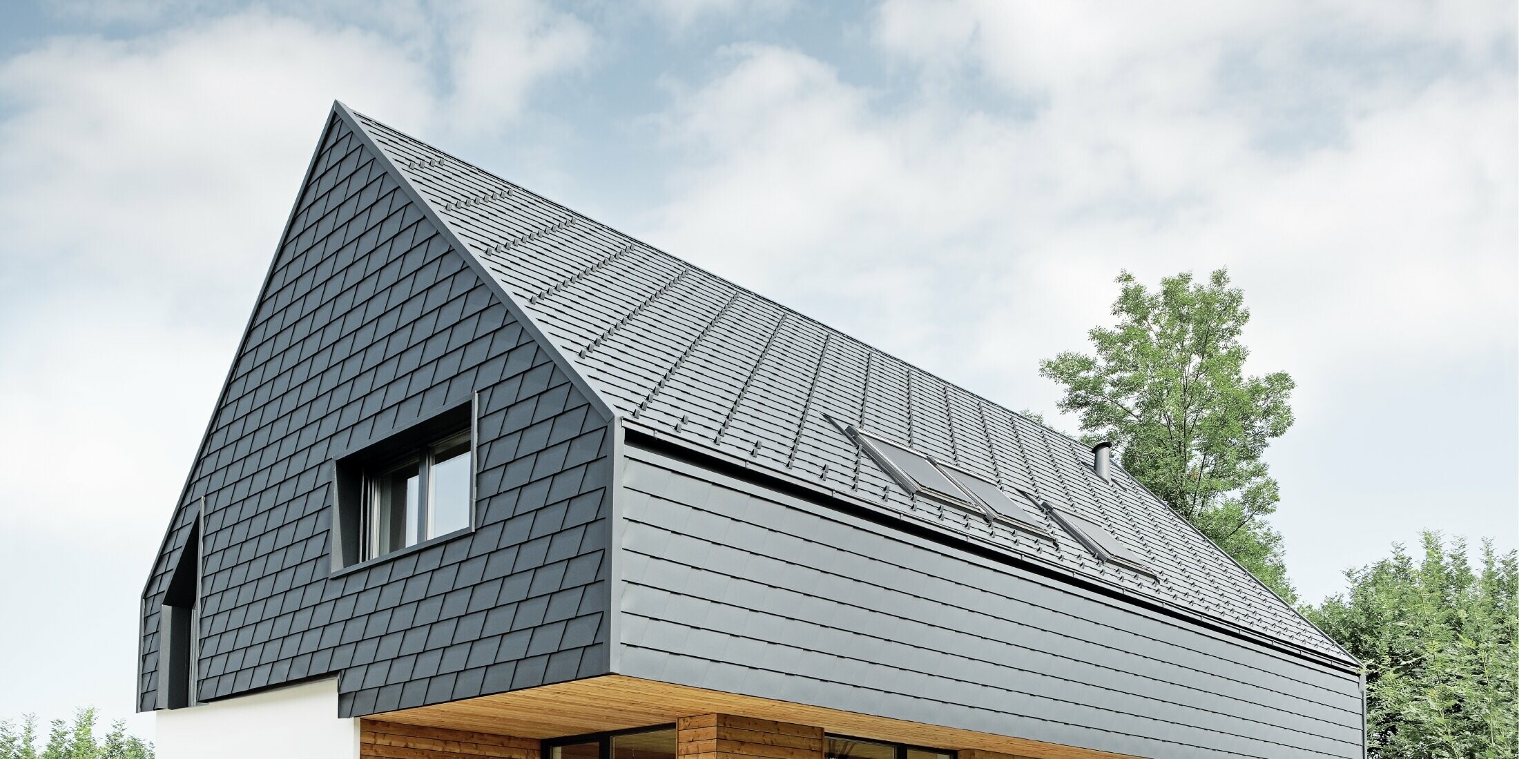 Detached house with gable roof, roofed with PREFA roof shingles in P.10 anthracite, the shingles were also installed on the façade on the upper floor and on the gable.