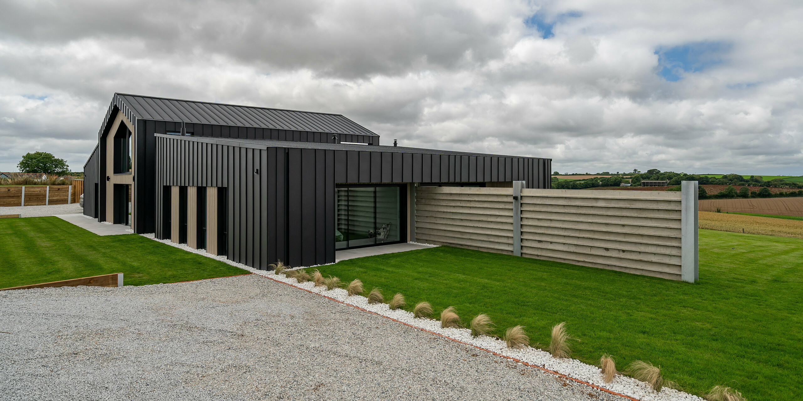 Side view of ‘The Hide’ in Cornwall with PREFALZ aluminium façade and roof in P.10 anthracite. The modern standing seam look harmonises with the clear lines of the building and the surrounding natural areas. The front garden and sheltered terrace emphasise the functional and stylish character of the house.