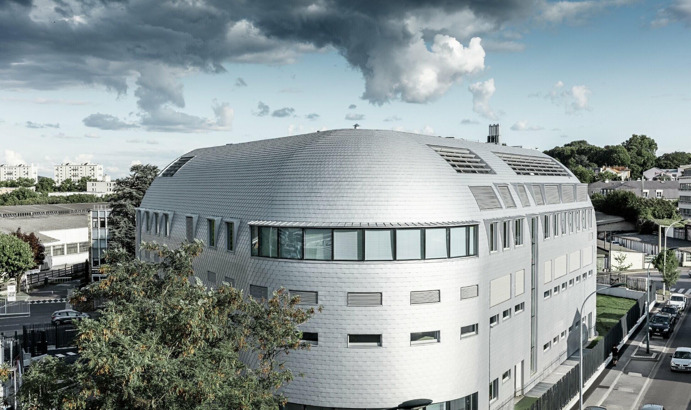 Commercial building with round dome and PREFA aluminium shingles in metallic silver.