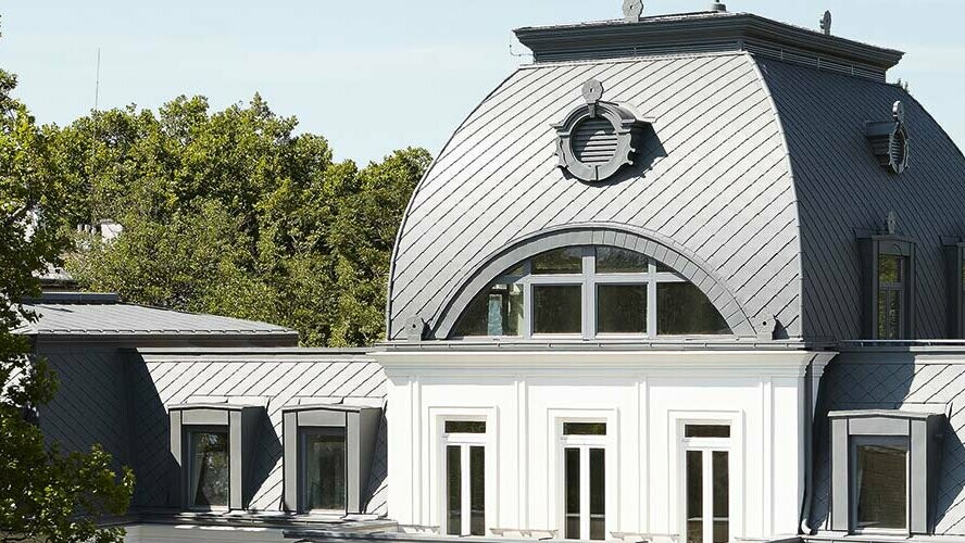 Mansard roof with dome of monument-protected building renovated with PREFA rhomboid roof tiles and Prefalz in P.10 light grey