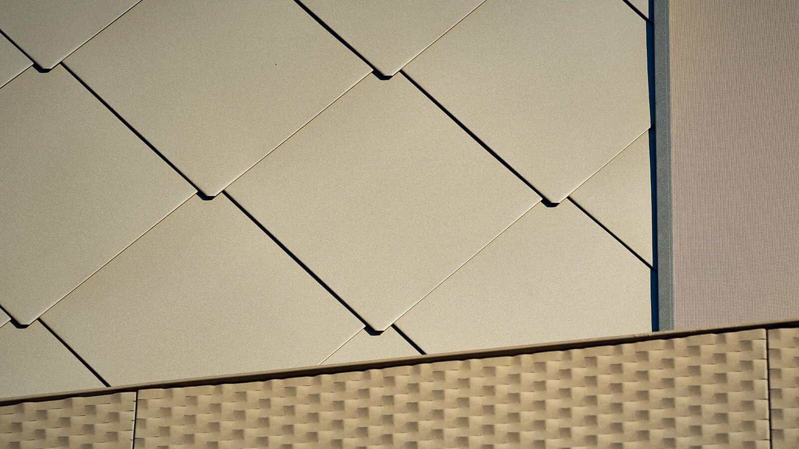 The picture shows a close-up of PREFA rhomboid façade panels 44 x 44 with the special coating P.10 Bronze.