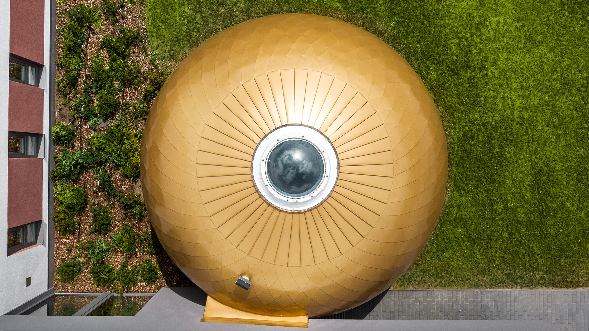 One of the round rooms with a central skylight from above: the plaster façade frames it in the bottom and in the left part of the photo, the lawn frames it in the upper and the right part of the photo.